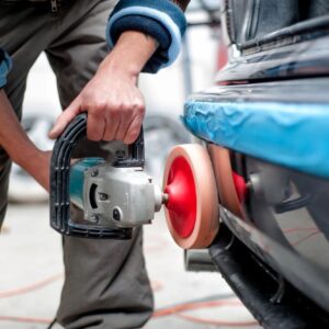 A person using an electric sander to polish the car.