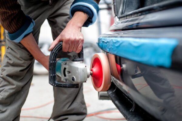 A person using an electric sander to polish the car.