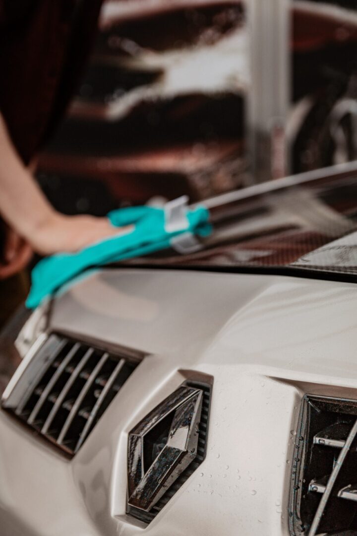 A person is cleaning the hood of a car.