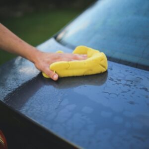 A person cleaning the hood of their car