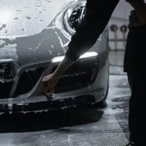 A person washing a car in the rain.