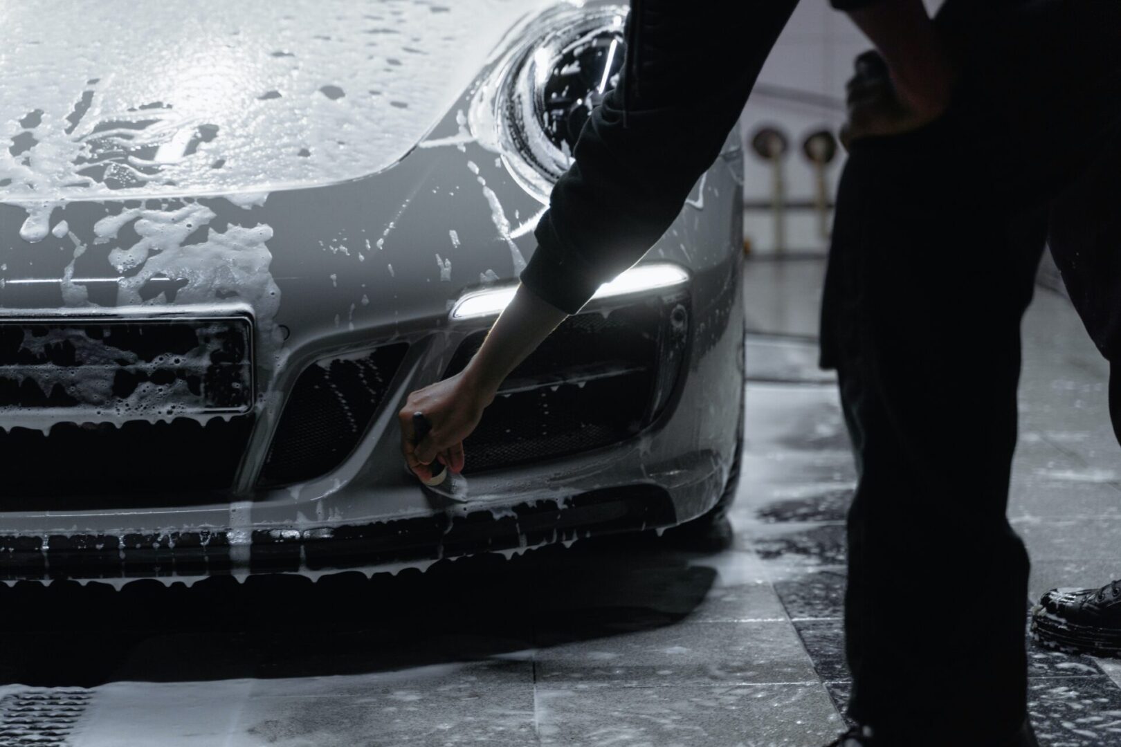 A person washing a car in the rain.