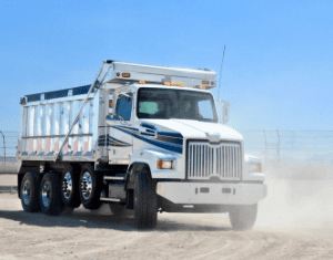 A dump truck driving down the road in the desert.