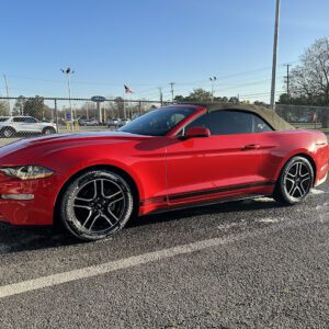 A red convertible parked on the side of a road.