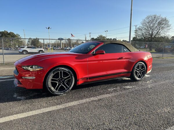 A red convertible parked on the side of a road.