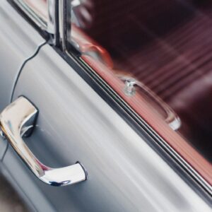 A silver door handle and window on a car.