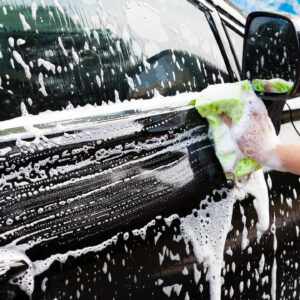 A person washing their car with soap and water.