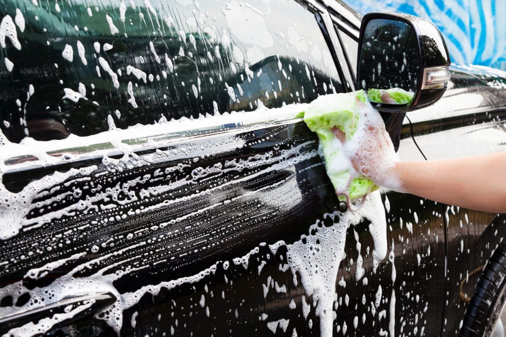 A person washing their car with soap and water.