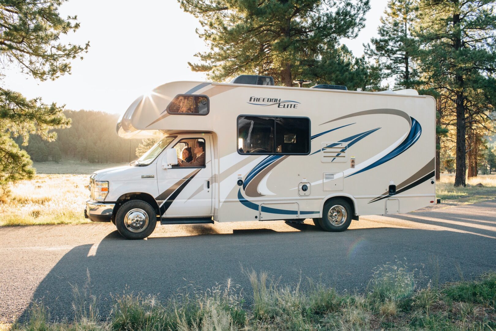 A white and blue rv is parked on the side of the road.